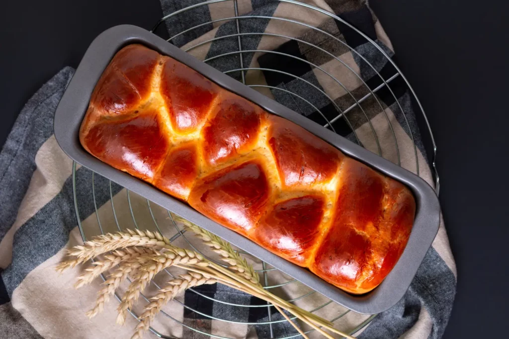 Golden brioche loaf with butter and jam on a wooden table