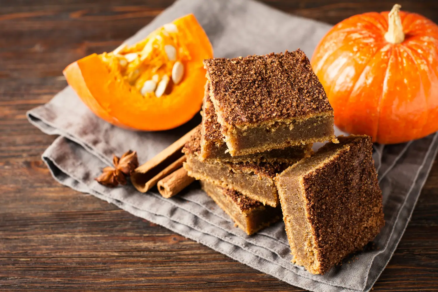 Freshly baked pumpkin bars topped with cream cheese frosting in a cozy fall kitchen setting.