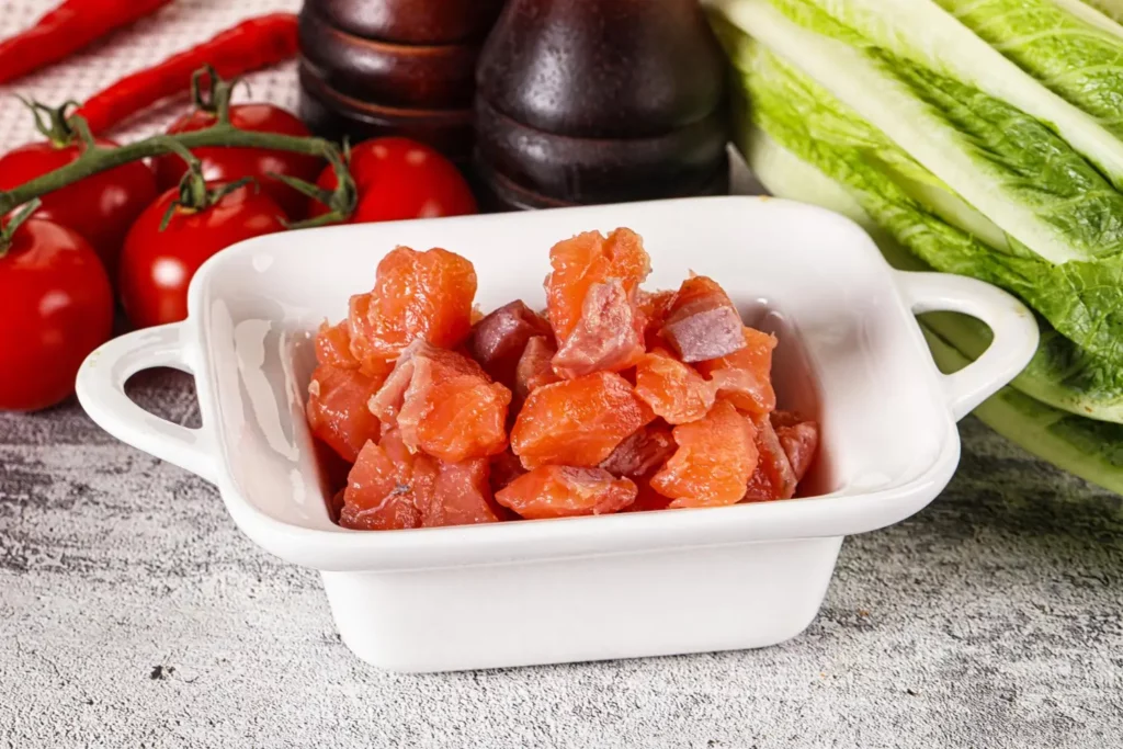 Cutting salmon into cubes on a wooden cutting board