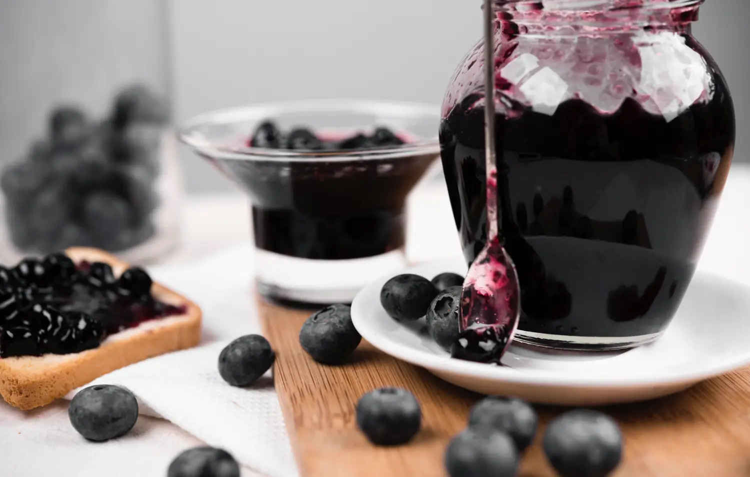 A bowl of homemade blueberry compote surrounded by fresh ingredients.