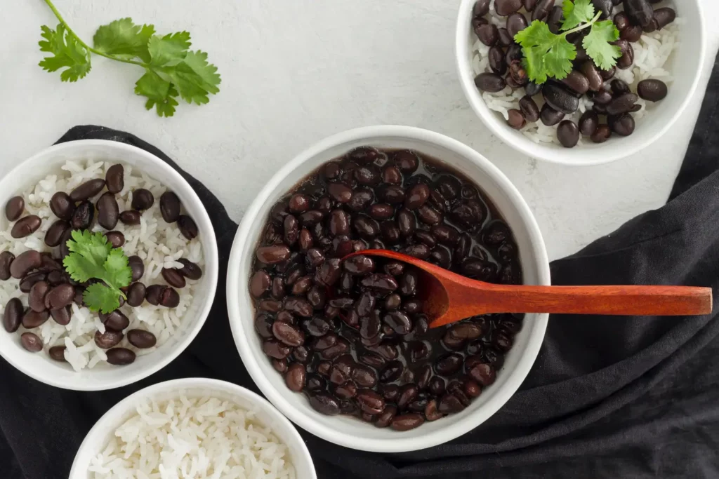 Bowl of Cuban black beans with rice, garnished with cilantro and lime.