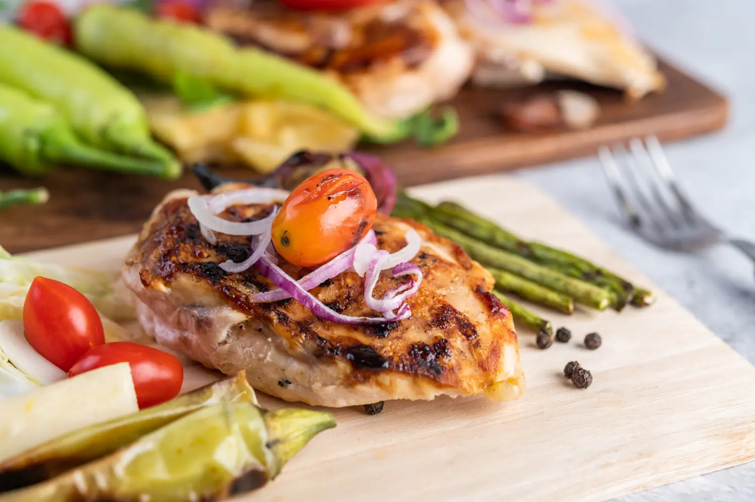 Grilled chicken thighs with char marks served with lemon wedges.