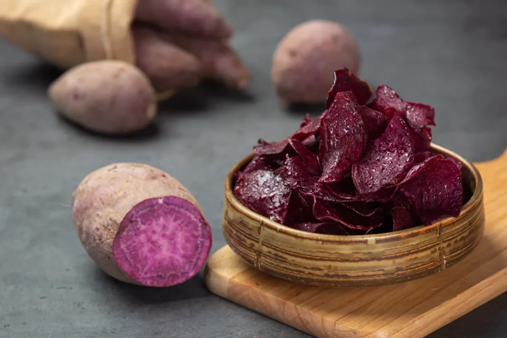 Raw purple sweet potatoes sliced open on a cutting board.