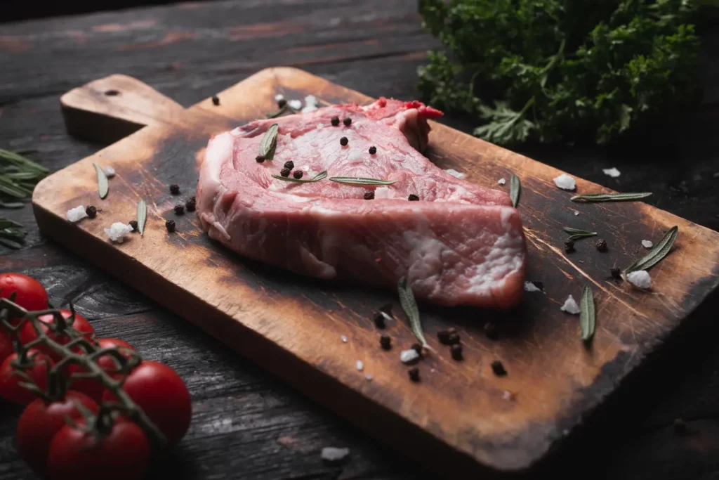 Grilled bison steak with spices on a wooden board