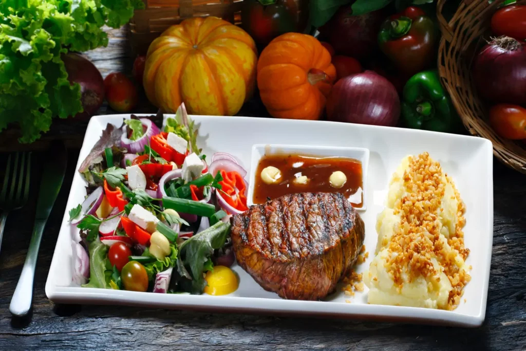 Steak dinner with mashed potatoes and roasted vegetables.