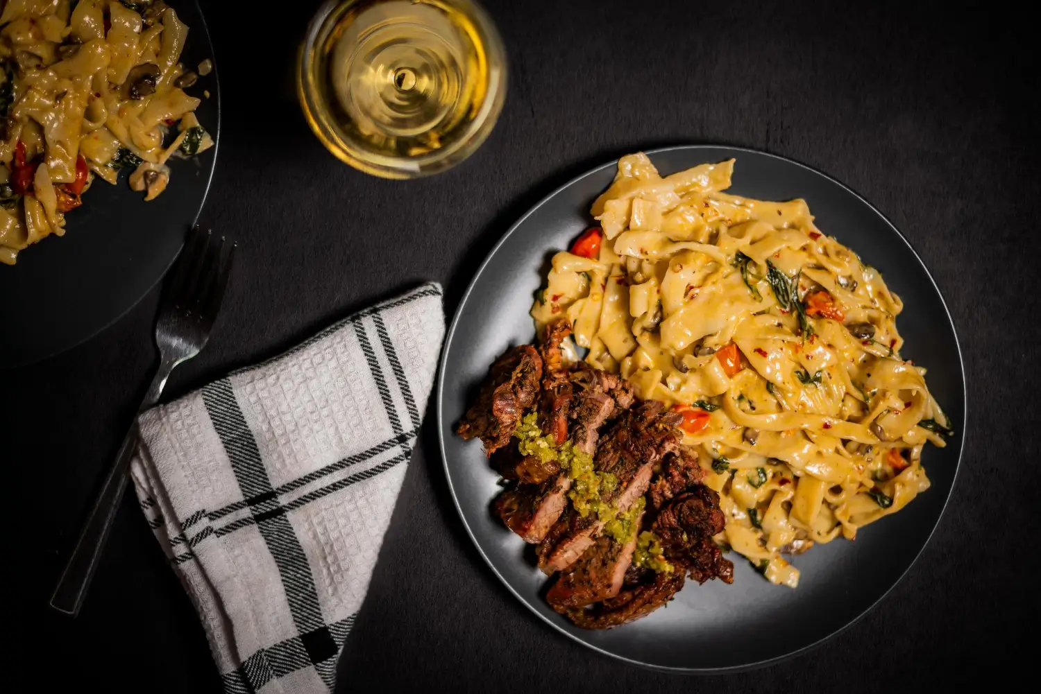 Creamy steak and pasta dinner with ribeye and garlic bread.