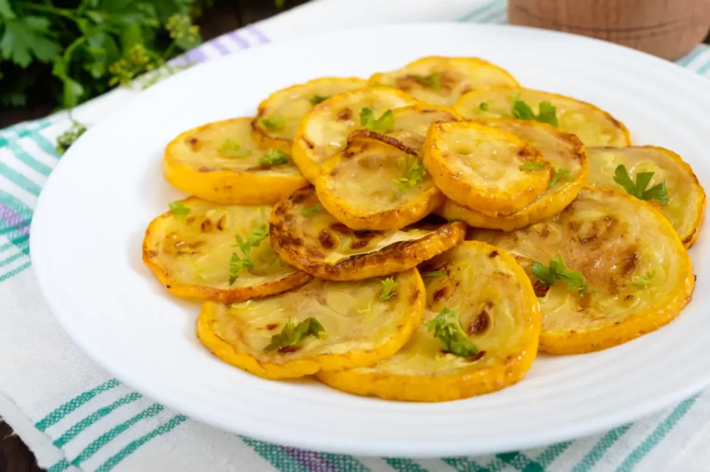 Plate of golden fried squash slices with dipping sauce.