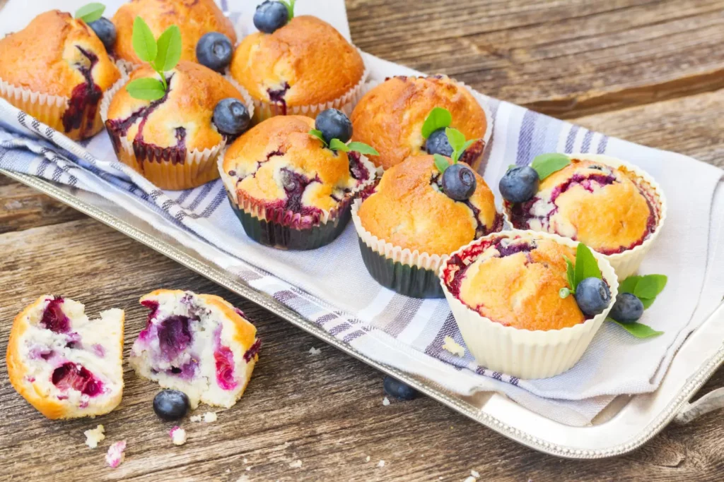 Freshly baked strawberry muffins cooling on a rack with scattered strawberries and baking ingredients.