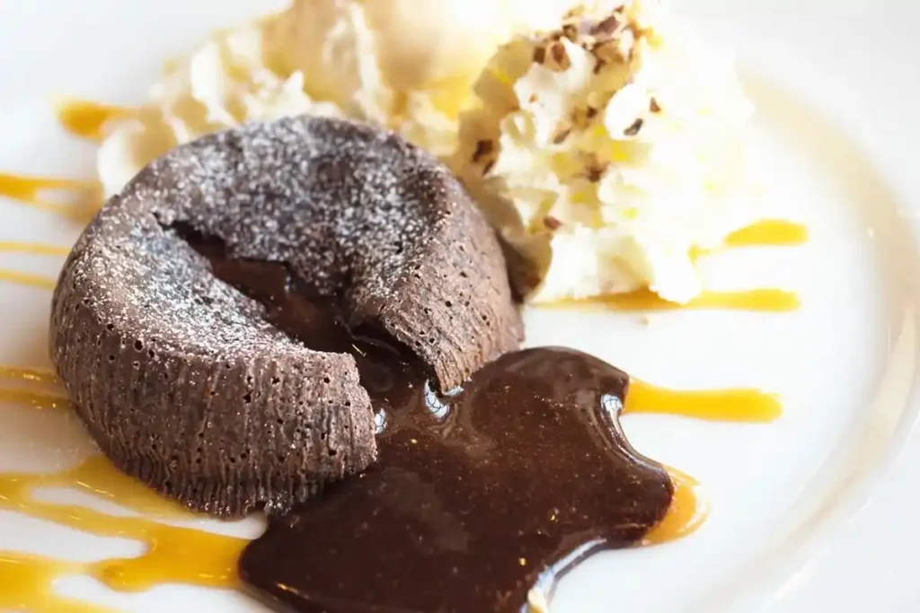 A chocolate lava cake with a gooey center, dusted with powdered sugar and served with vanilla ice cream