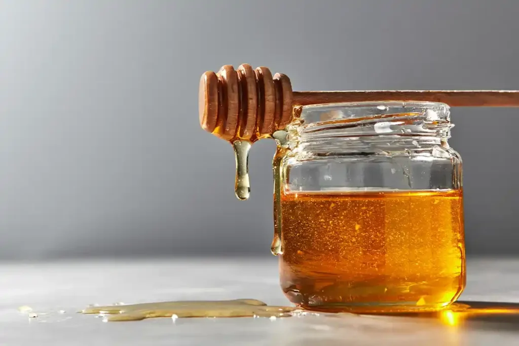 A jar of homemade honey simple syrup with a honey dipper