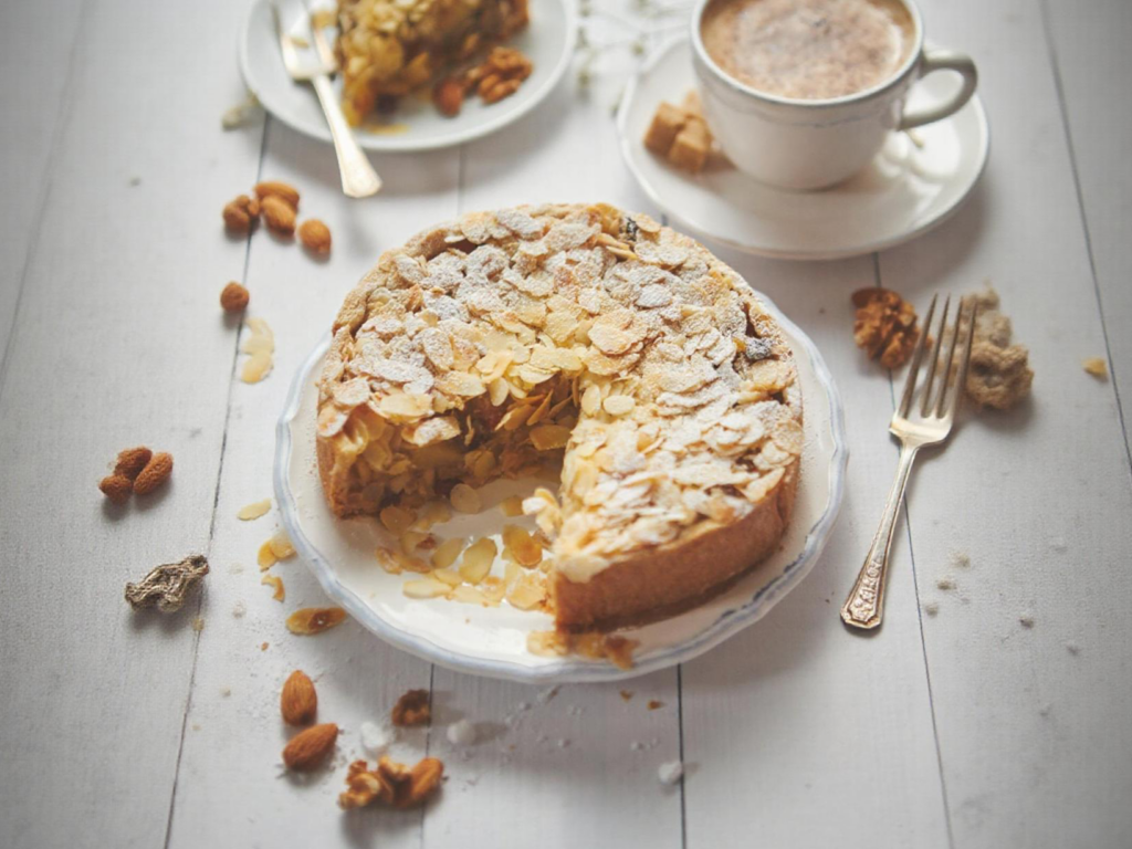 Almond nut cake with powdered sugar and almonds on a wooden table.