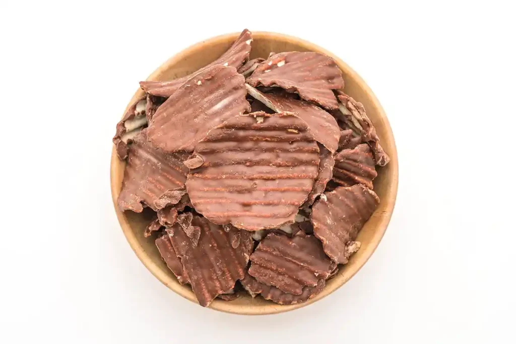 Potato chip being dipped into melted chocolate.