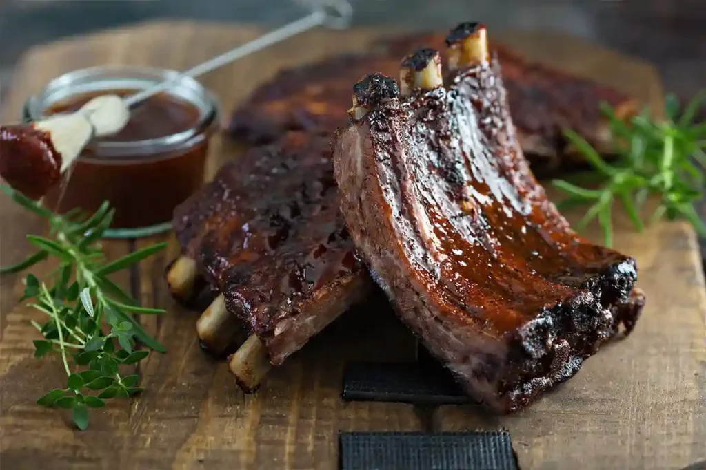 Meaty smoked beef ribs with a smoky crust, glistening with spices and resting on a platter