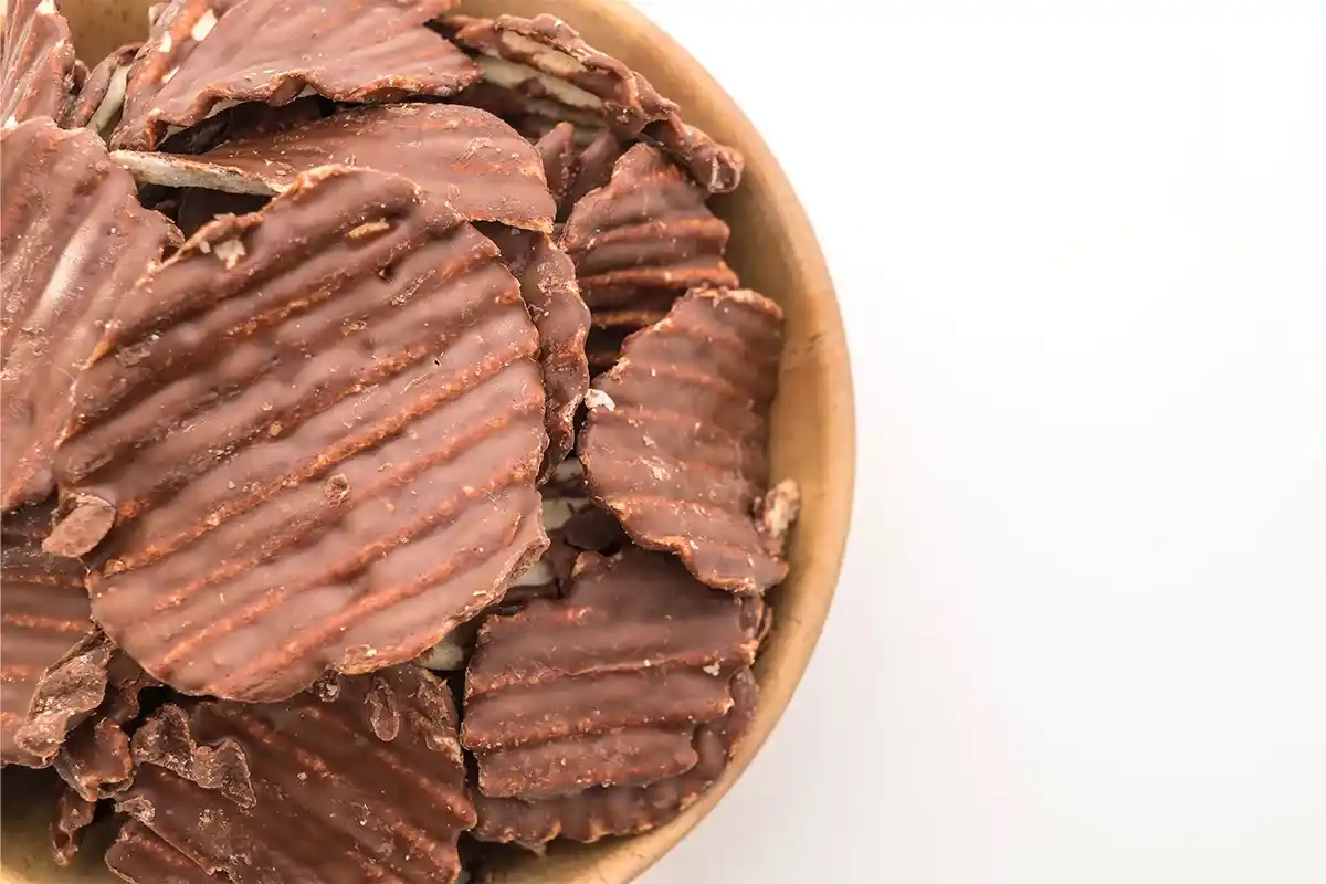 Bowl of chocolate-covered potato chips sprinkled with sea salt.