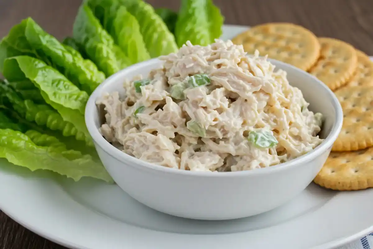 Bowl of creamy Chicken Salad Chick Classic Carol recipe with crackers