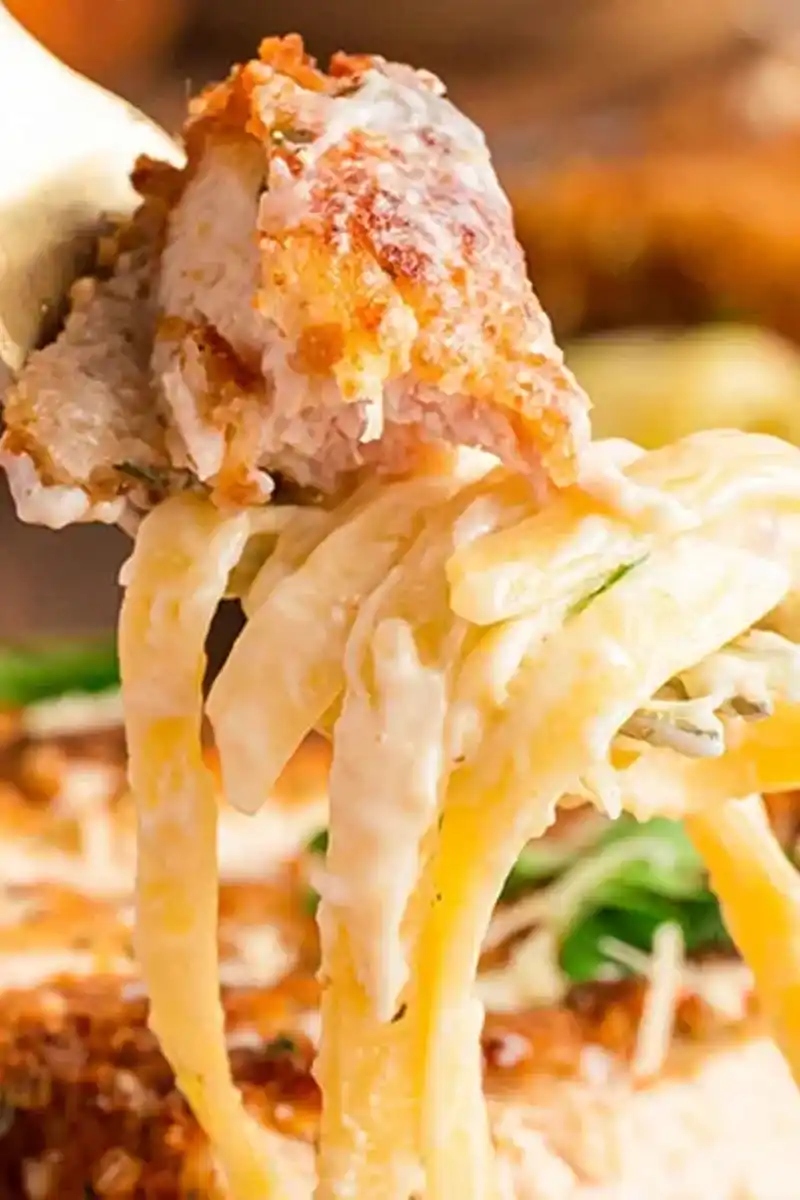 Crispy Chicken Fritta recipe Close-up of Crispy Chicken Fritta and fettuccine Alfredo on a fork.