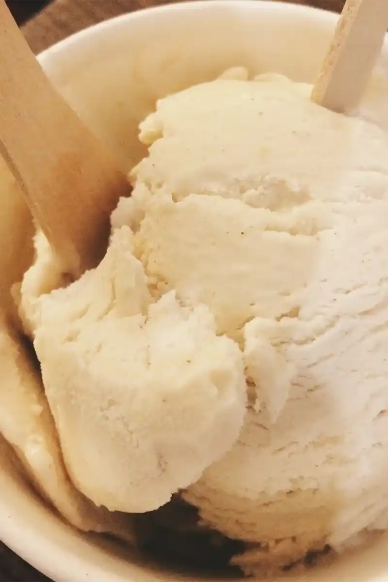 Homemade Vanilla Ice Cream Scoops Scoops of homemade vanilla ice cream with two wooden spoons in a white bowl